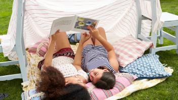 Mother and daughter reading outside under a backyard tent