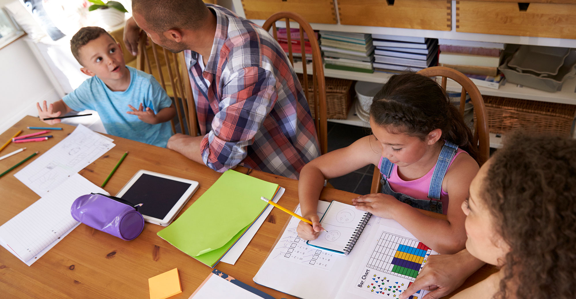 Birds-eye view of mother, father, son, and daughter at the homework table