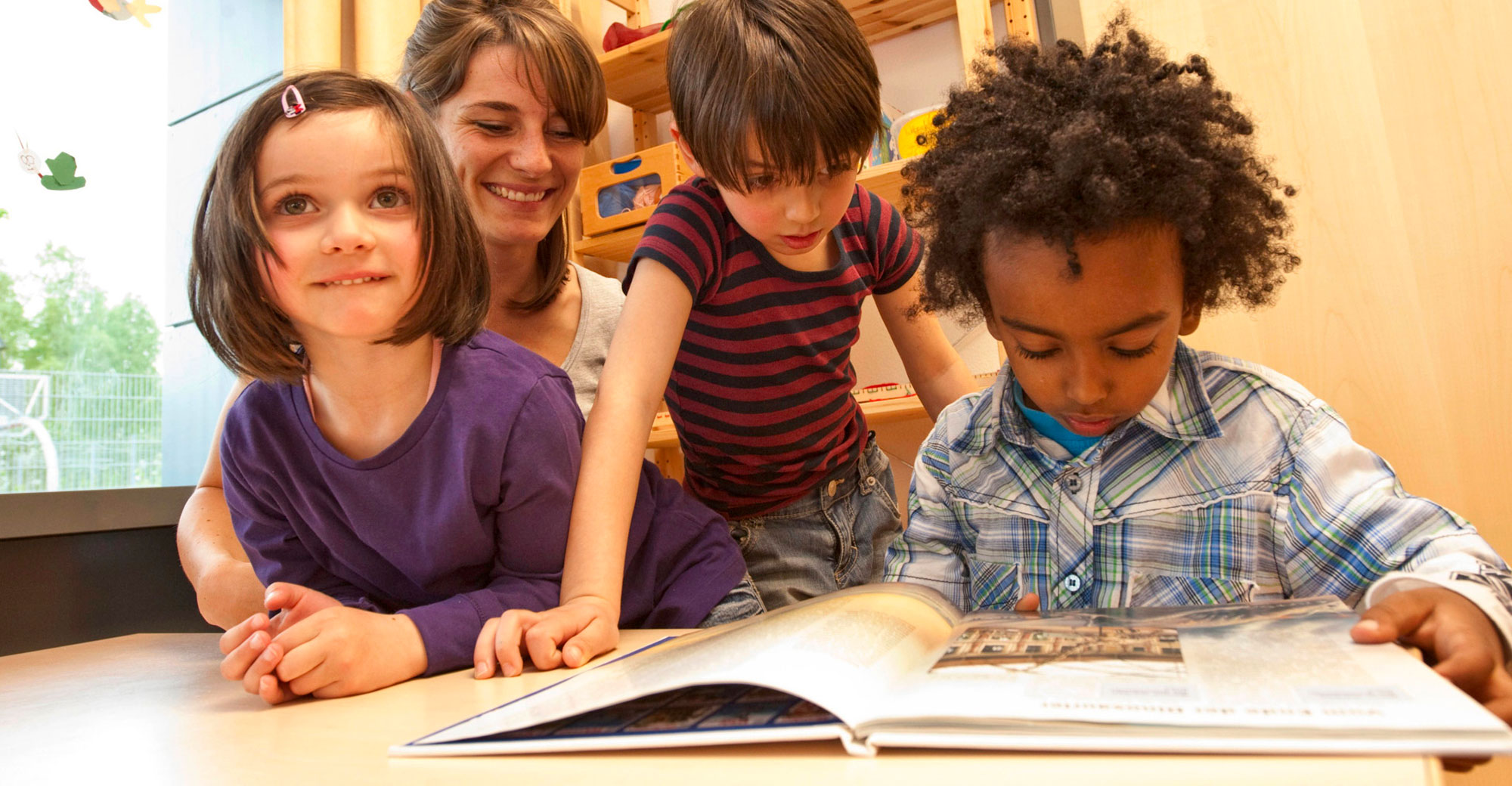 Elementary teacher with three of her students looking at a picture book