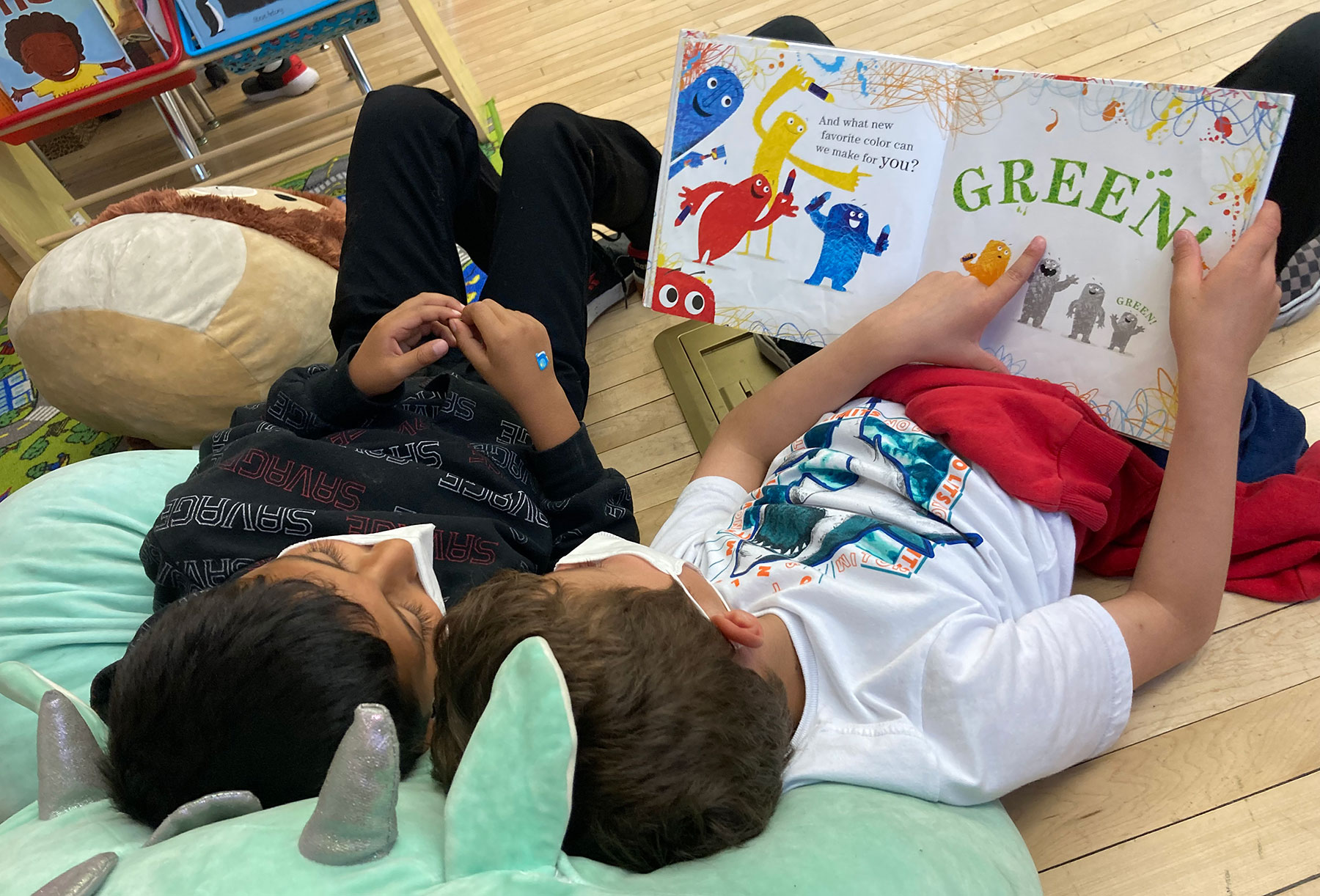 Two elementary children reading picture book on beanbag chairs