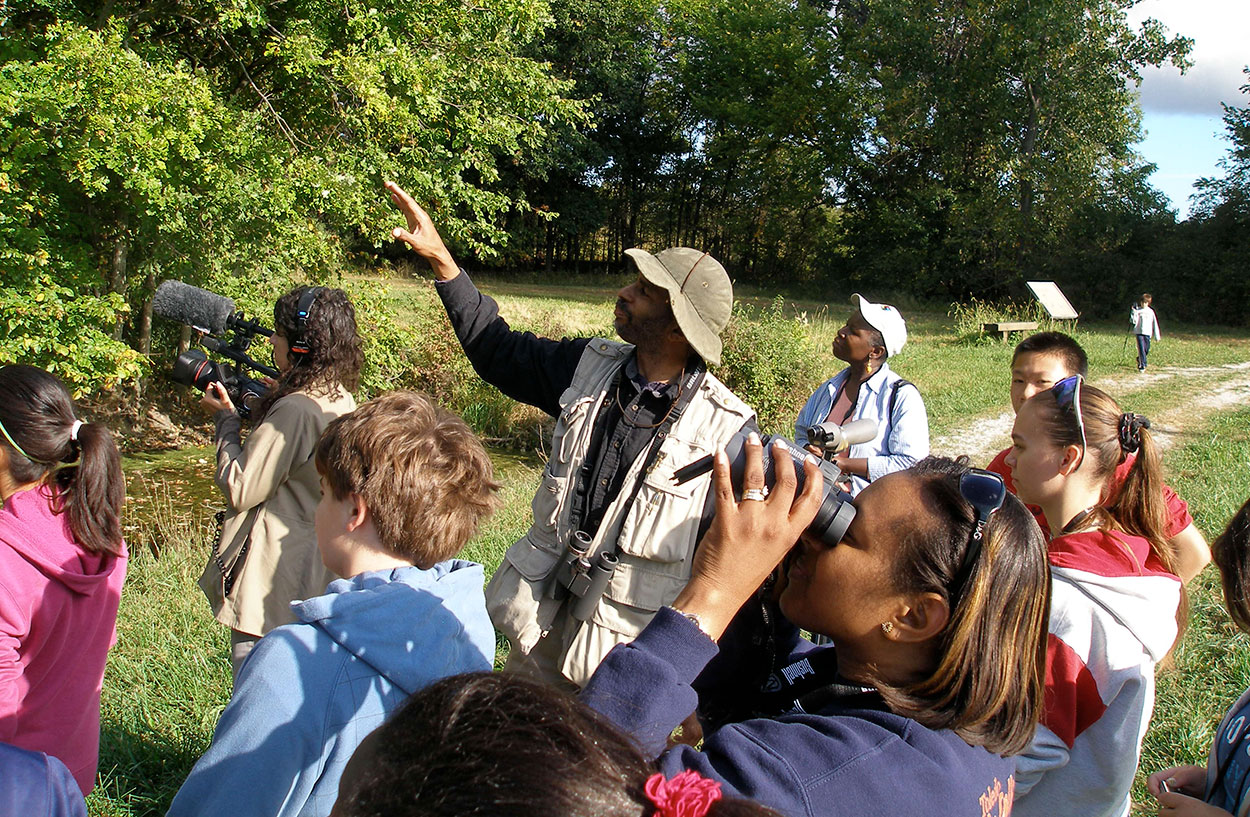 Ornithologist and wildlife biologist John C. Robinson outside leading a multicultural, multiage birding group