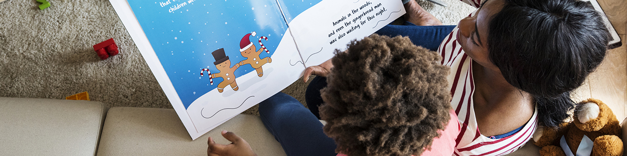 African American mother reading picture book to kindergarten son