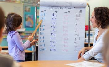 First grader at board reading 3-letter words for teacher