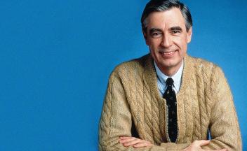 Portrait of Fred Rogers wearing a tan zip-up cardigan