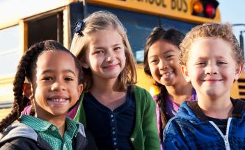 Diverse group of kids in front of yellow school bus