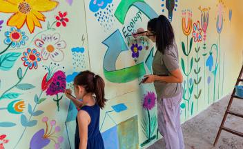 Mother and daughter painting an environmental mural together