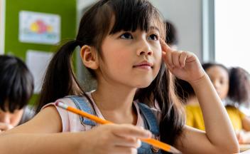 Elementary student in class thinking pensively about the lesson