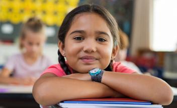 Young Latina student smiling in the classroom at her desk