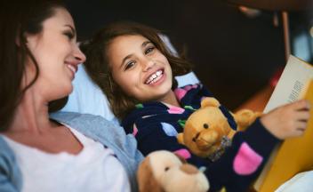 mother and daughter reading books together with stuffed animals
