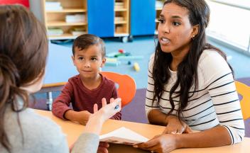 Parent with elementary child talking to teacher at school