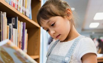 Young girl looking at picture book in the library