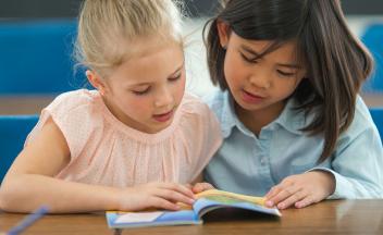 Two elementary students reading a beginning readers book