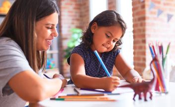 preschool girl writing with adult
