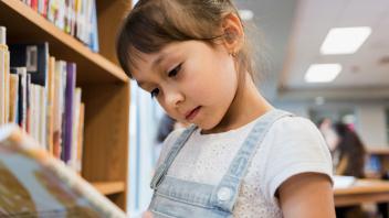 Young Latina reading a picture book in the library