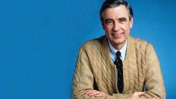 Portrait of Fred Rogers wearing a tan zip-up cardigan