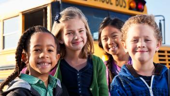 Diverse group of kids in front of yellow school bus