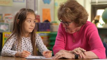 Reading tutor working with a first grade student at a desk