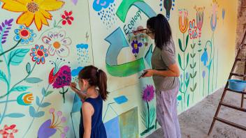 Mother and daughter painting an environmental mural together