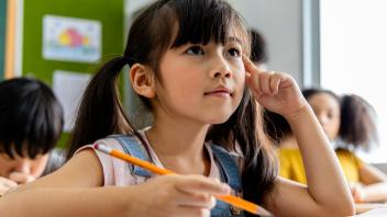 Elementary student in class thinking pensively about the lesson
