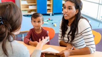 Parent with elementary child talking to teacher at school