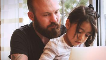 Elementary aged girl looking at laptop with her father