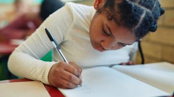 elementary school student writing at her desk