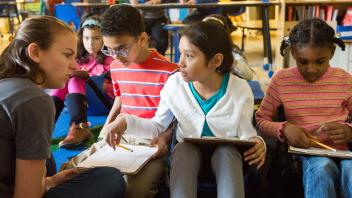 elementary teacher discussing a text with three students in class