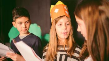 elementary student with paper crown engaged in reader's theater