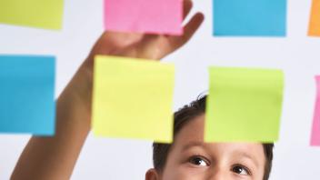 elementary student arranging colorful sticky notes on a board