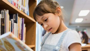 Young girl looking at picture book in the library