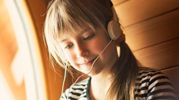 Young girl with earbuds listening to audiobook