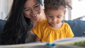 Mom reading picture book to preschool daughter