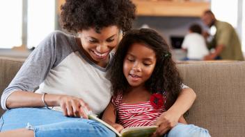 Mom reading chapter book with second grade daughter