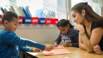 elementary teacher working with two students on reading assignment
