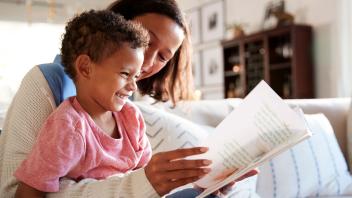 Parent reading picture book to young son