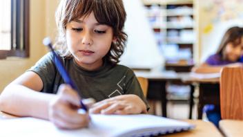Young boy writing in class
