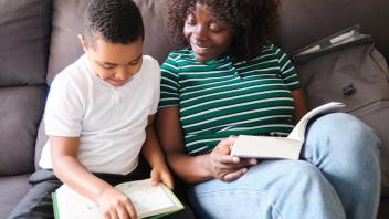 mother and son reading side by side on the couch