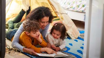 mother reading with her two kids in bedroom with tent